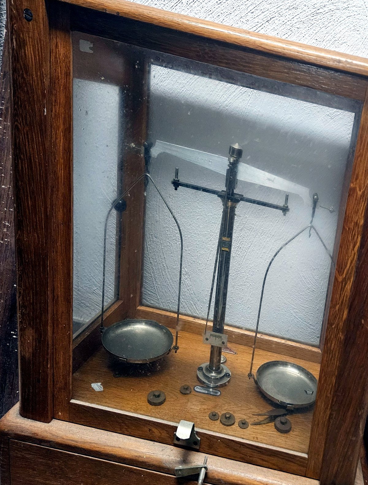 Historische Präzisionswaage im verglasten Holzgehäuse mit zwei Waagschalen und Gewichtssatz