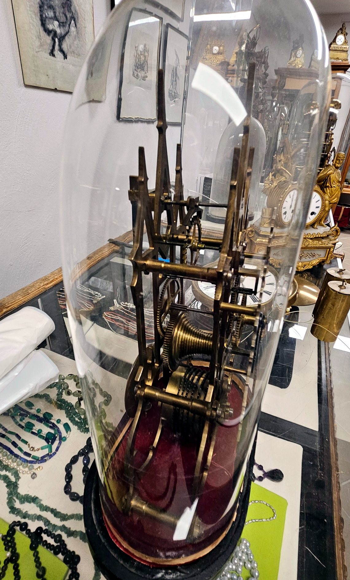 Seitenansicht einer englischen Skelettuhr unter Glasdom mit sichtbarem Werk und Pendel