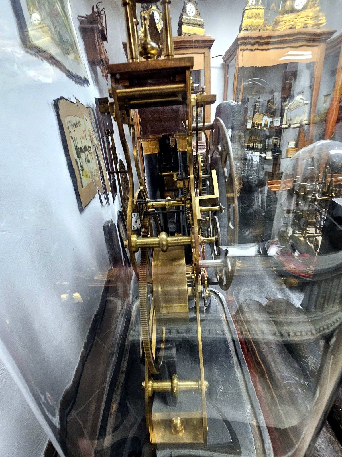 Seitliche Ansicht der englischen Skelettuhr unter Glasdom mit sichtbarem Messingwerk und Räderwerk