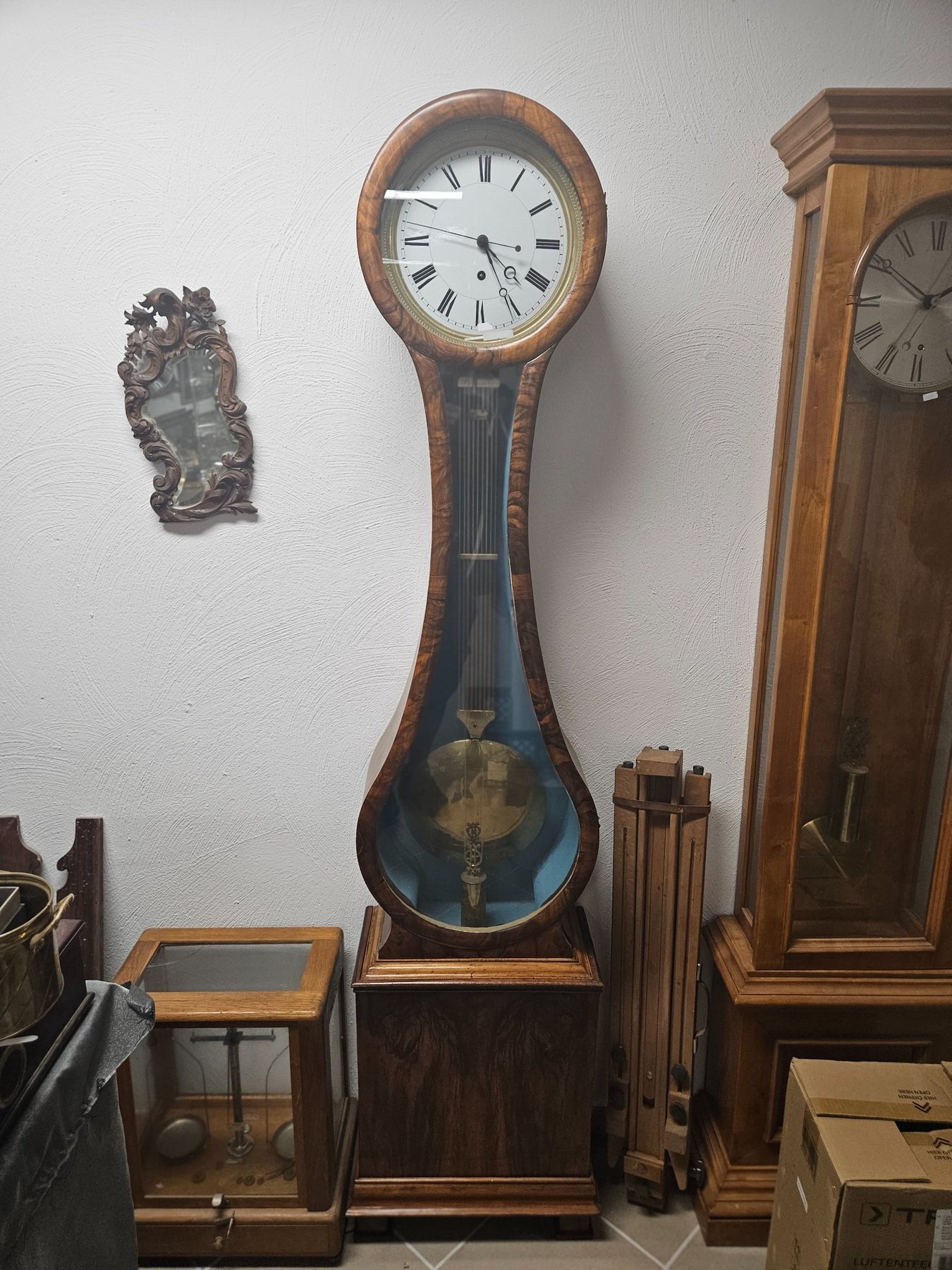 Regulatoruhr mit zentraler Sekunde, sichtbarem Pendel und elegantem Holzgehäuse.