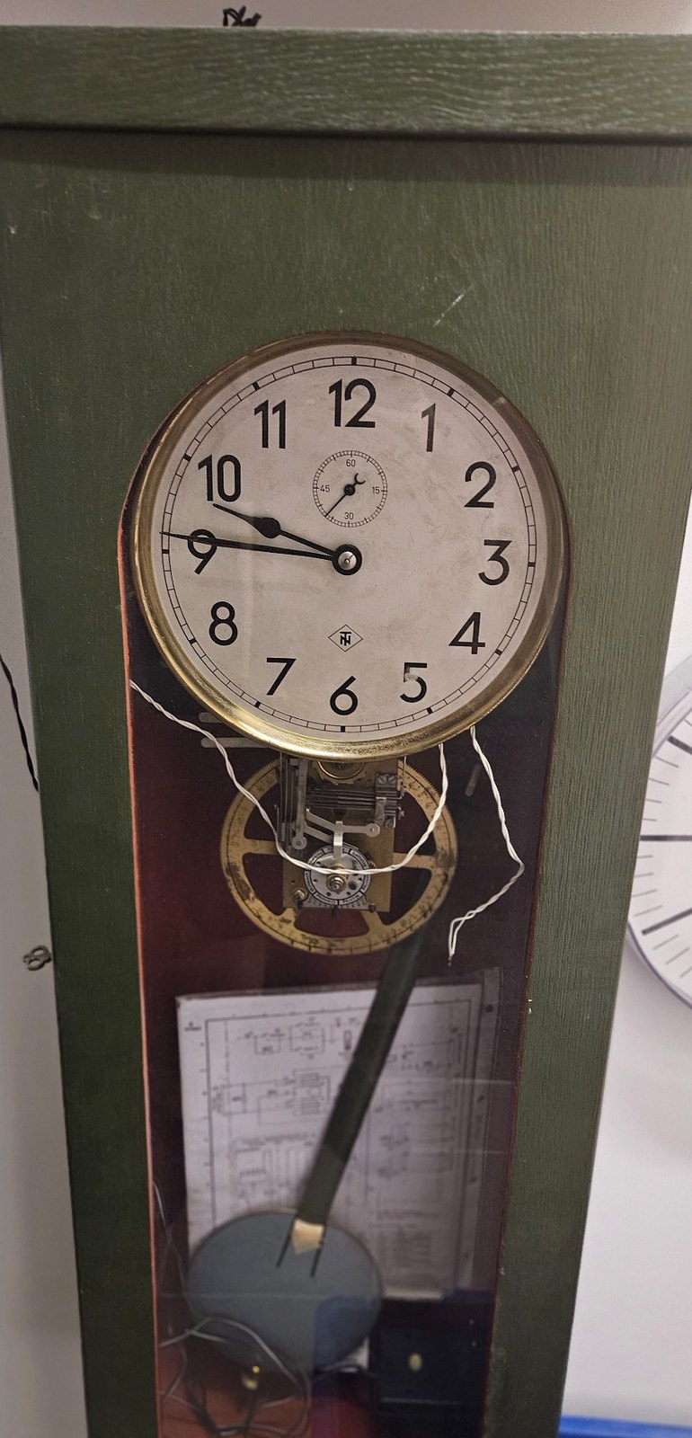 Telenorma-Mutteruhr mit grünem Holzgehäuse, Pendel und zentraler Sekunde